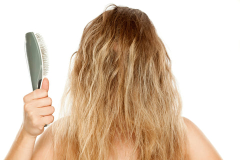 blonde lady with tangled hair holding brush