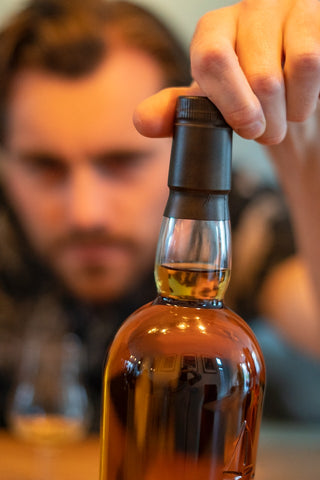 man putting lid on bottle of alcohol