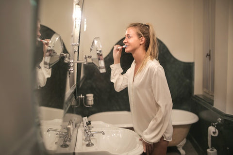 woman brushing her teeth in bathroom