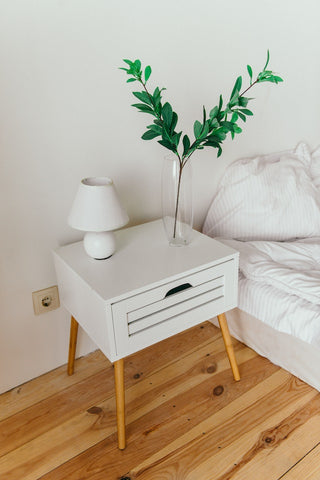 bed side table with plant and lamp on it