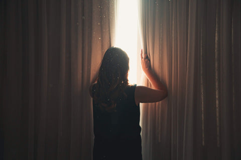 lady opening curtains in morning with sunlight