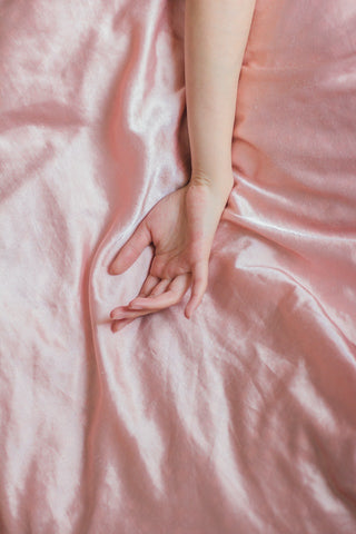 hand on pink silk sheet