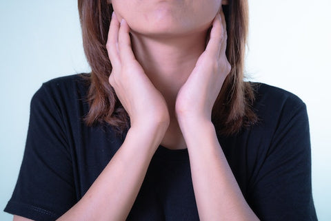 woman with hands on her neck in discomfort