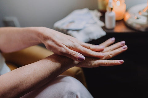 woman moisturising her hands and arms with oil