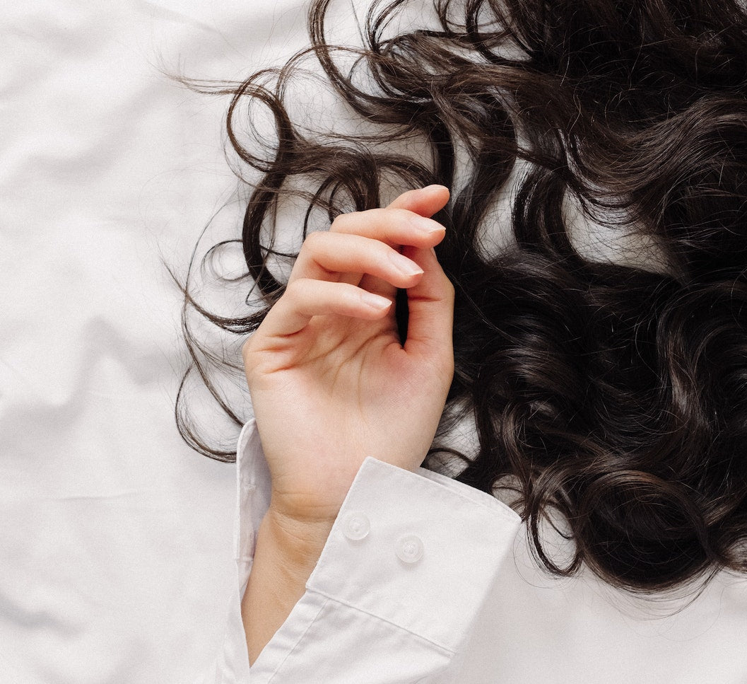 relaxed hand with hair in the background on a bed