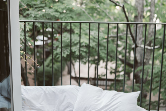 balcony bed with green trees in background