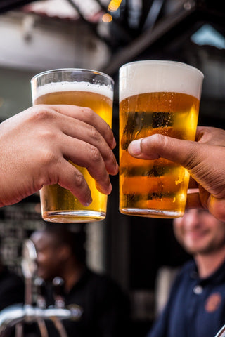 two pints of beer being held against each other