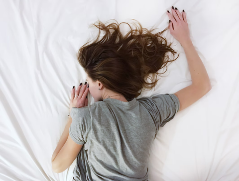 Woman laying with hair spread on silk sheets